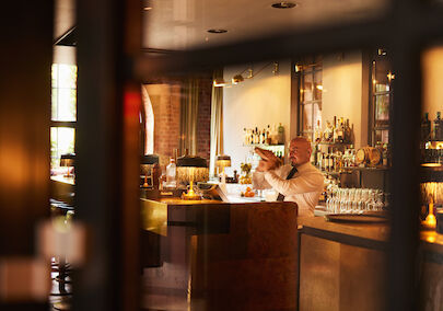 Barkeeper mixt hinter dem Tresen der Bar Mangold einen Drink.