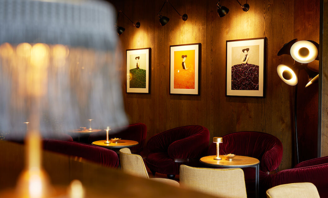 Einrichtung der Bar Mangold mit Tischleuchte, Samtsesseln und Wandbildern