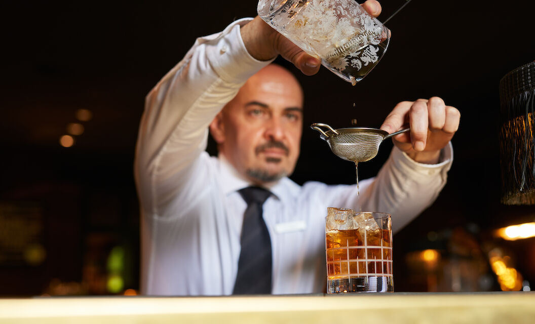 Barkeeper gießt einen Drink in ein Tumblerglas.