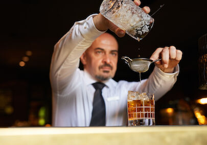 Barkeeper gießt einen Drink in ein Tumblerglas.