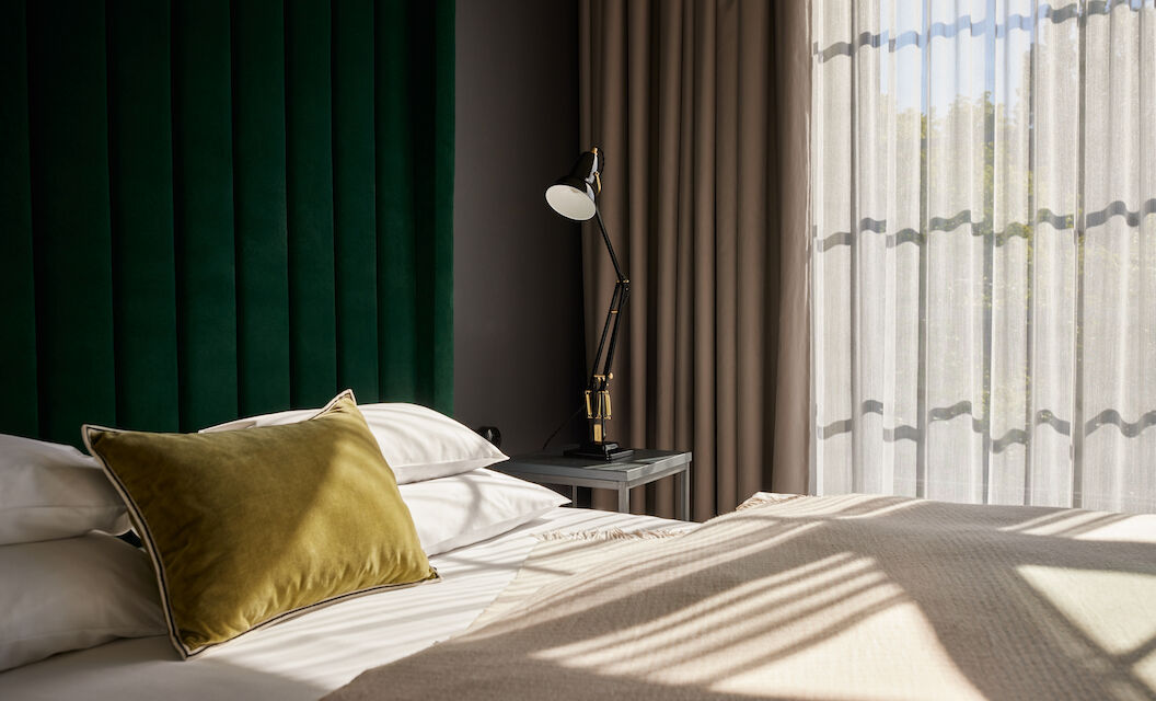 Sonnenschein fällt durch die großen Fenster auf das Bett im Loft