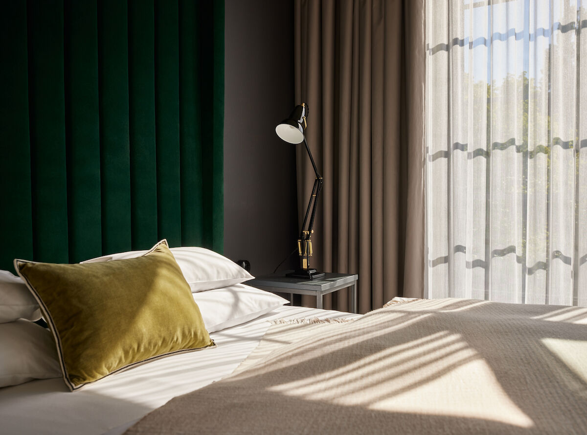 Sonnenschein fällt durch die großen Fenster auf das Bett im Loft