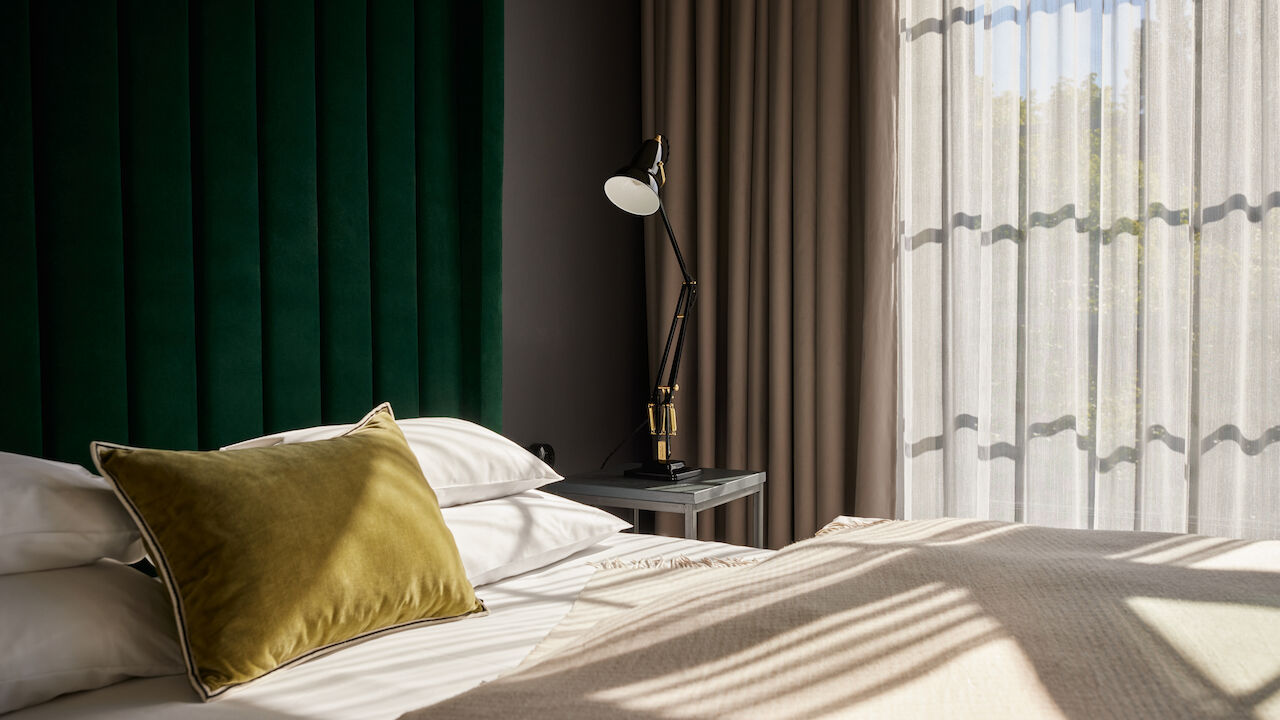 Sonnenschein fällt durch die großen Fenster auf das Bett im Loft