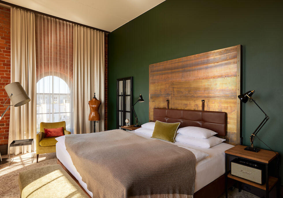 Blick auf das Doppelbett im L Loft des Gastwerk Hotel Hamburg mit Schneiderpuppe daneben