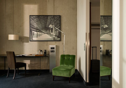 Zimmer M Loft im Gastwerk Hotel Hamburg mit grünem Sessel neben dem Schreibtisch