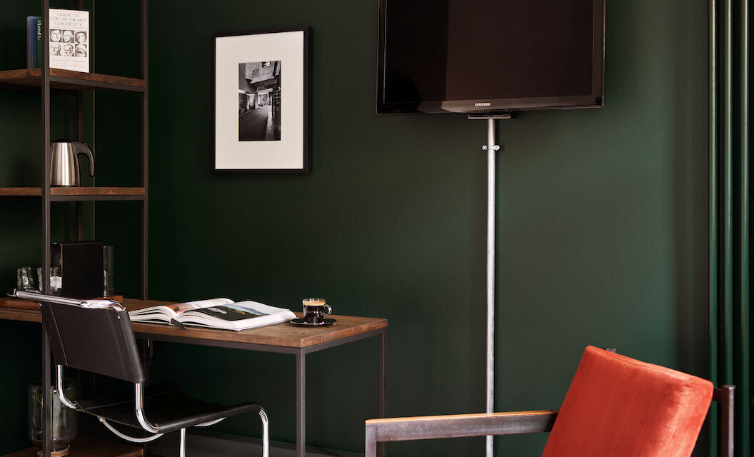 Zimmer S Loft im Gastwerk Hotel Hamburg mit Schreibtisch und rotem Sessel daneben