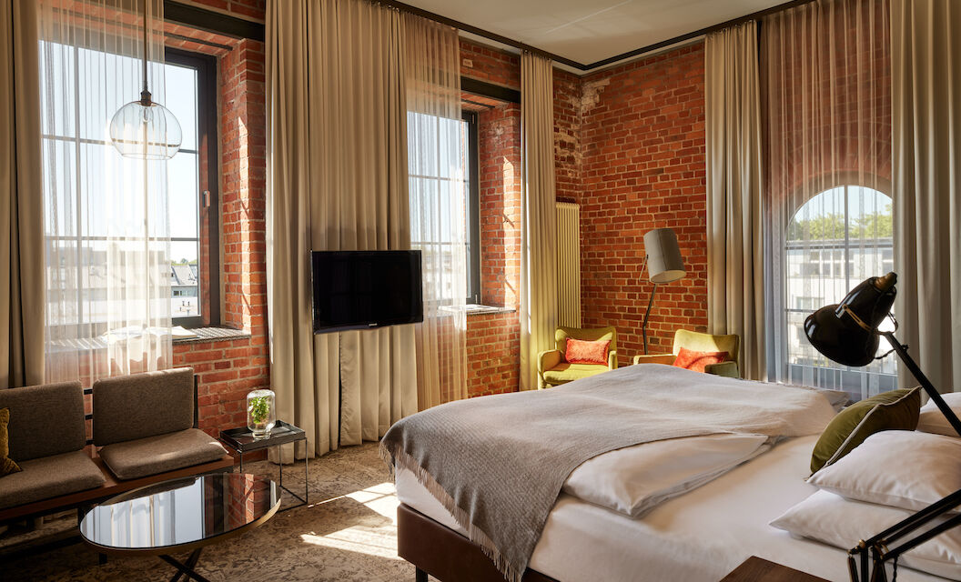 L Loft des Gastwerk Hotel Hamburg mit Bett, Backsteinwand und gelben Sesseln