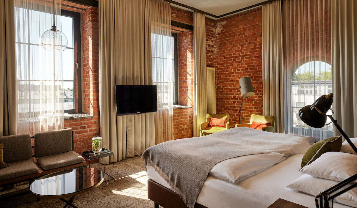 Gastwerk Hotel Hamburg Zimmer L Loft 552 02 L Loft des Gastwerk Hotel Hamburg mit Bett, Backsteinwand und gelben Sesseln