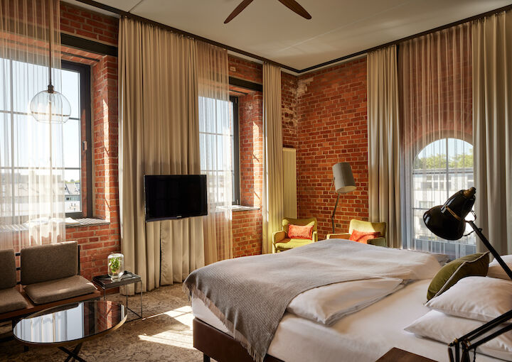 L Loft des Gastwerk Hotel Hamburg mit Bett, Backsteinwand und gelben Sesseln