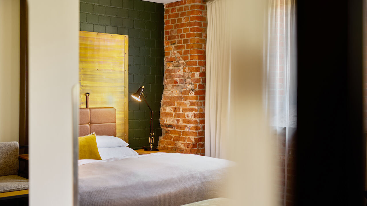 L Loft mit großem Bett im Anschnitt und Backsteinwand im Hintergrund