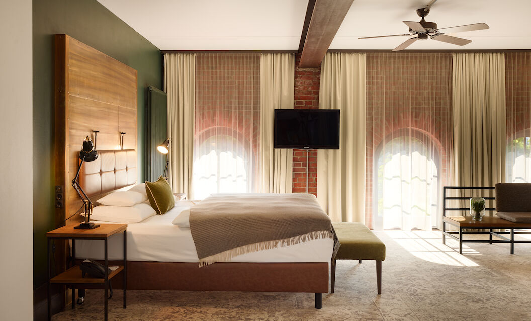 XL Loft im Gastwerk Hotel Hamburg mit Blick aufs Bett, Backsteinwand und Rundbogenfenster