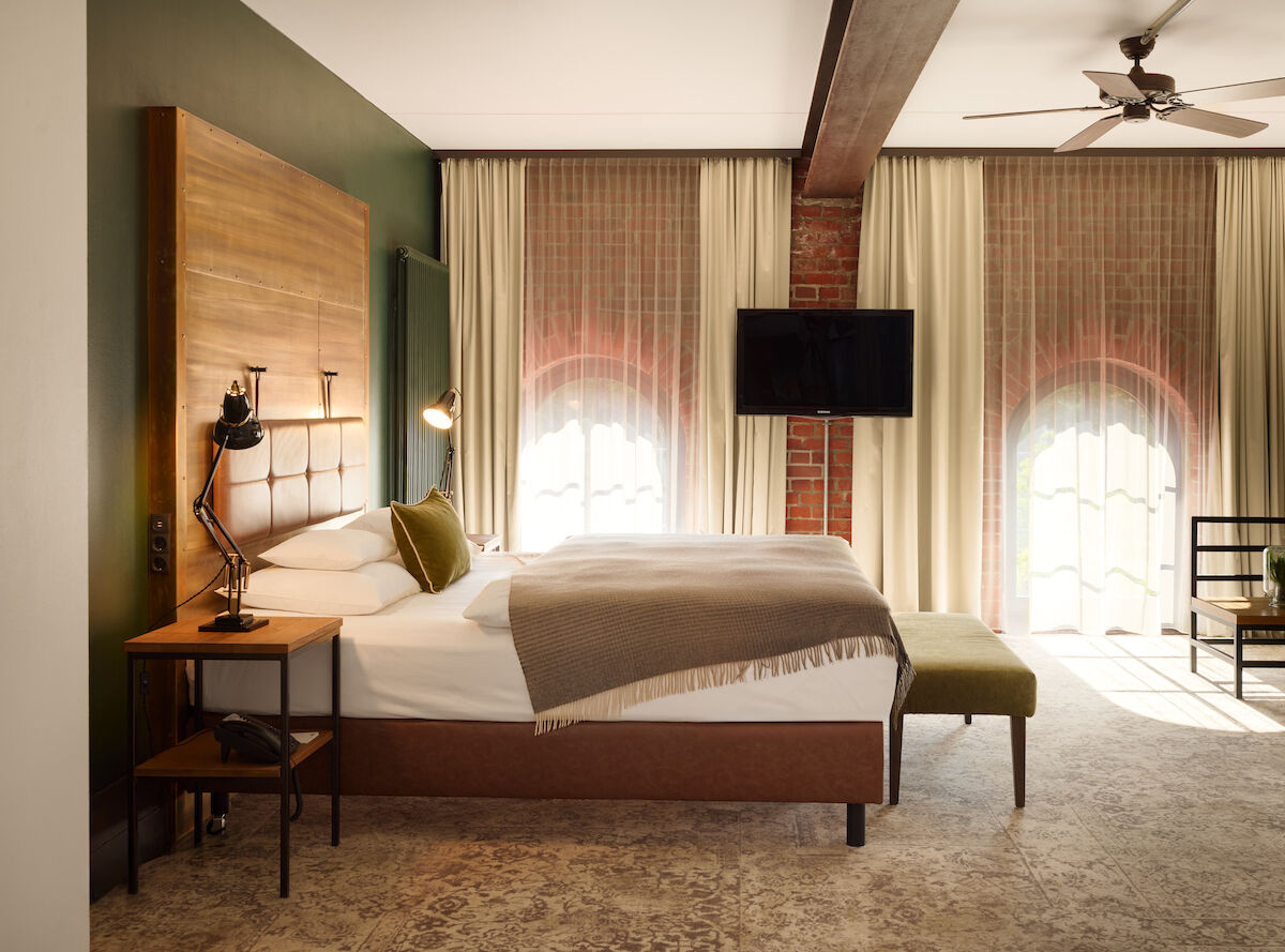 XL Loft im Gastwerk Hotel Hamburg mit Blick aufs Bett, Backsteinwand und Rundbogenfenster