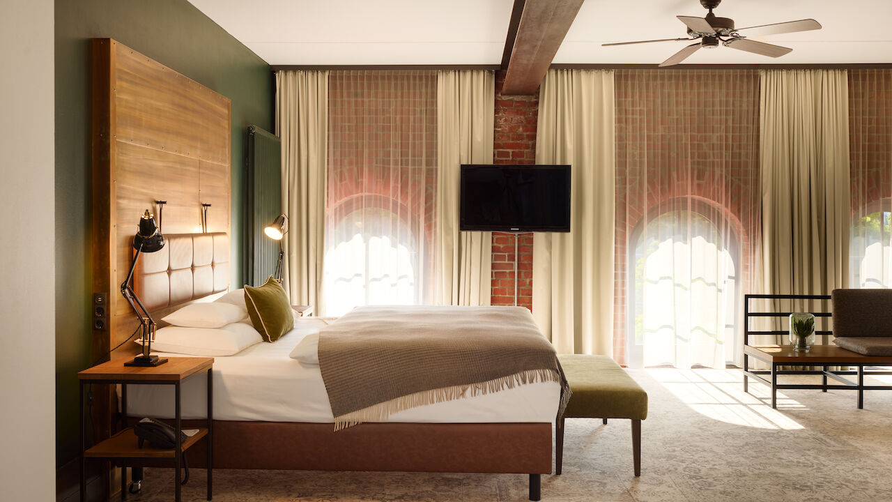 XL Loft im Gastwerk Hotel Hamburg mit Blick aufs Bett, Backsteinwand und Rundbogenfenster