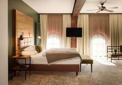 XL Loft im Gastwerk Hotel Hamburg mit Blick aufs Bett, Backsteinwand und Rundbogenfenster
